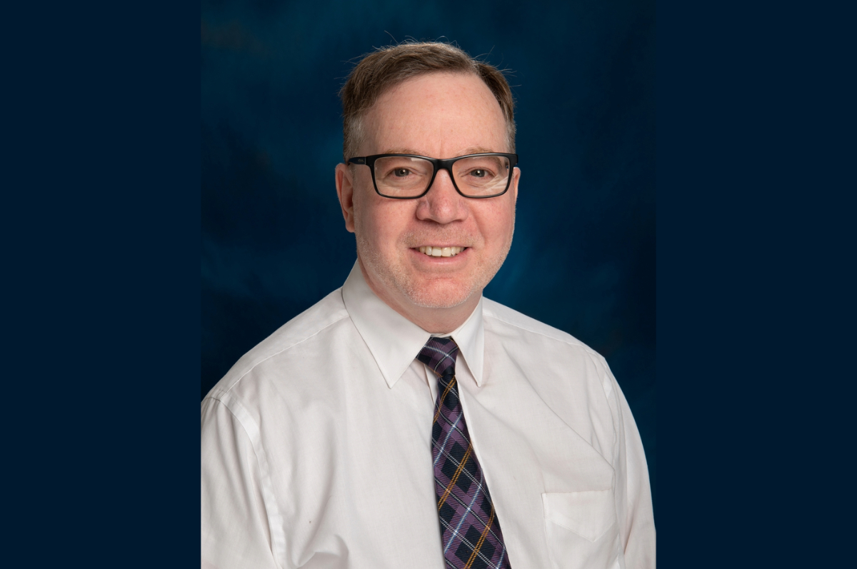 portrait of man with glasses on dark blue background